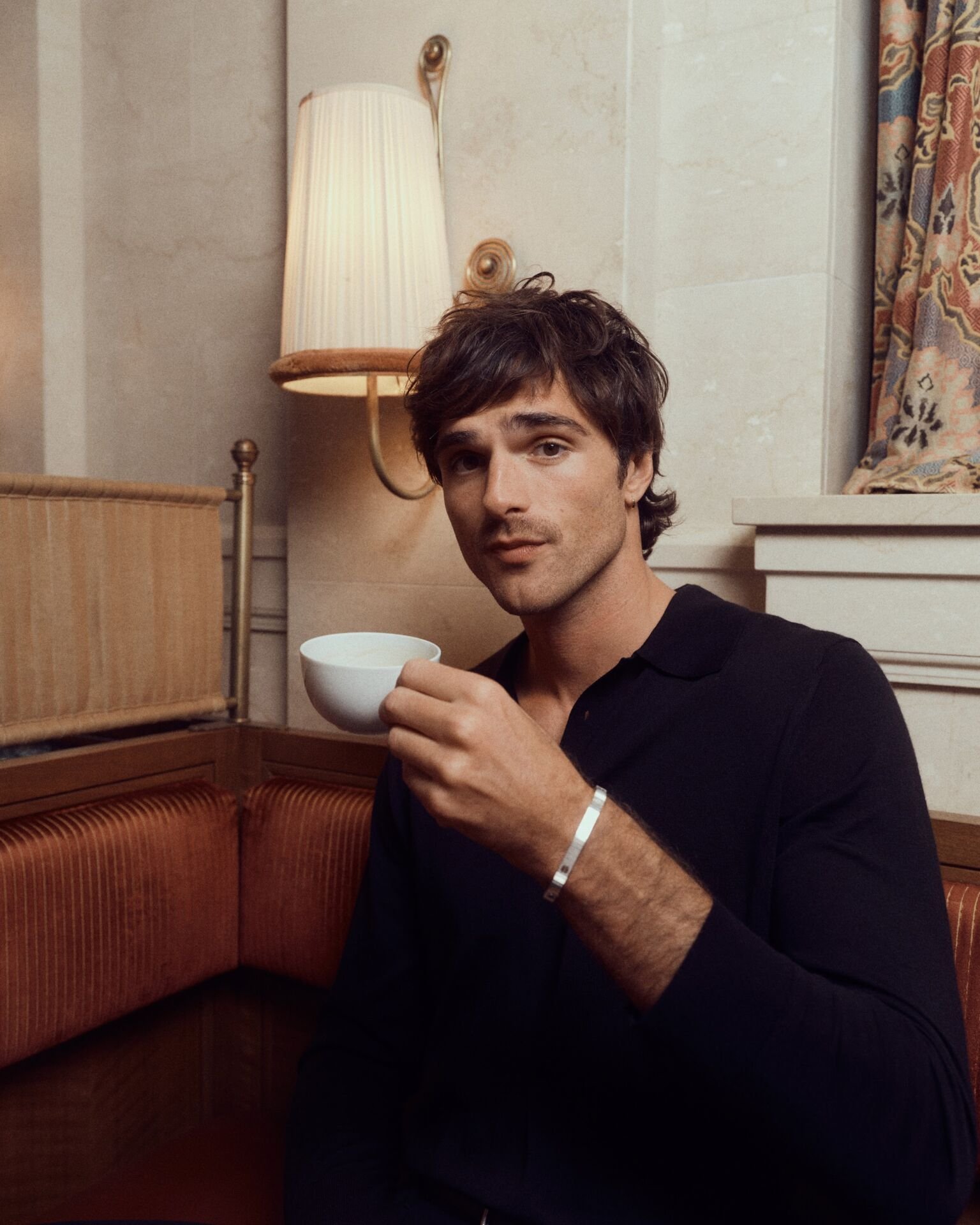 Jacob Elordi with a teacup, wearing the LOVE bracelet