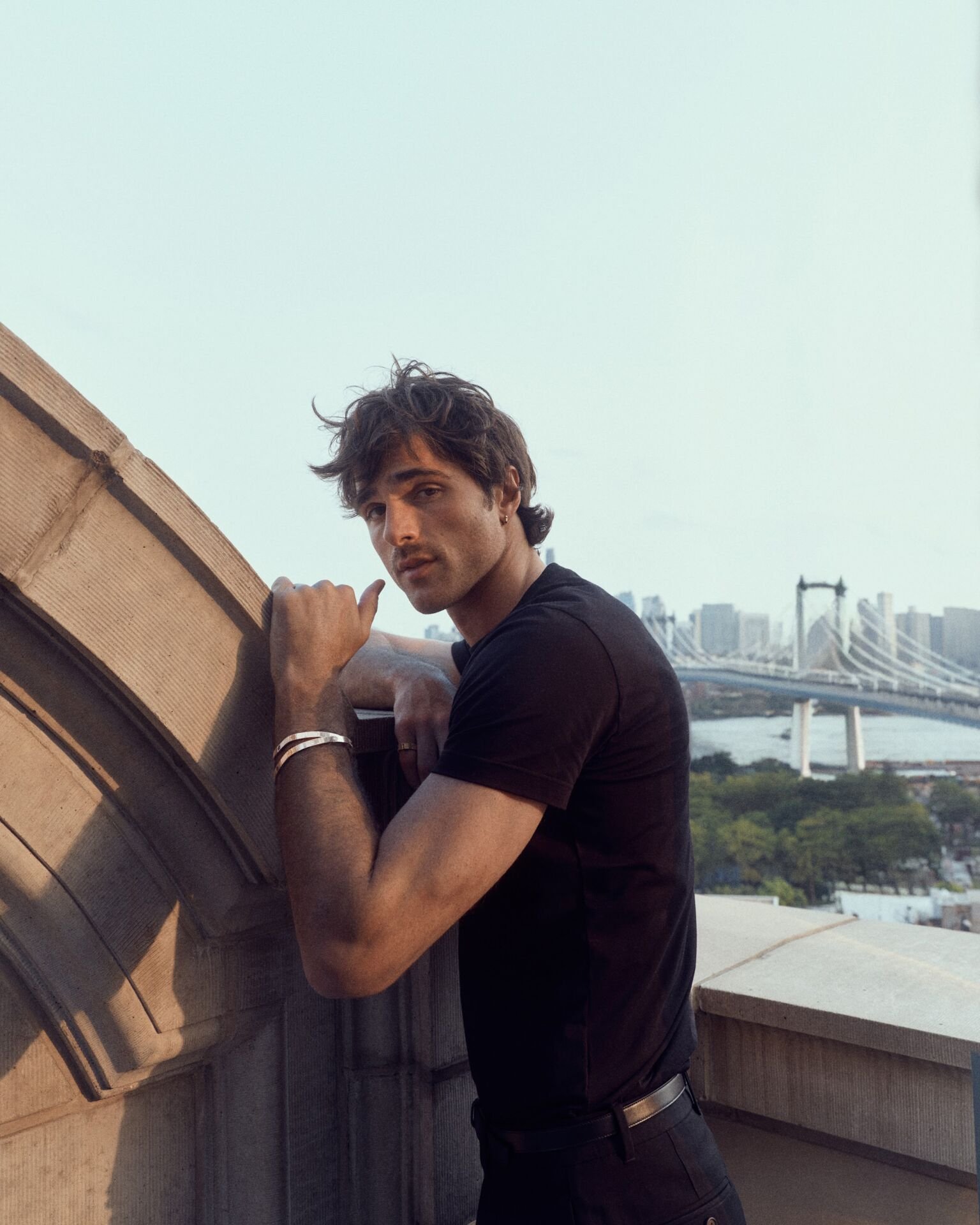 Jacob Elordi on a rooftop wearing the LOVE bracelet