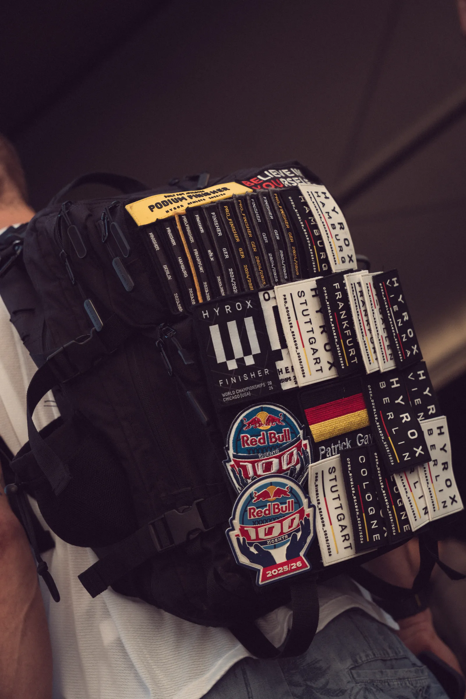 A black backpack covered in HYROX race patches
