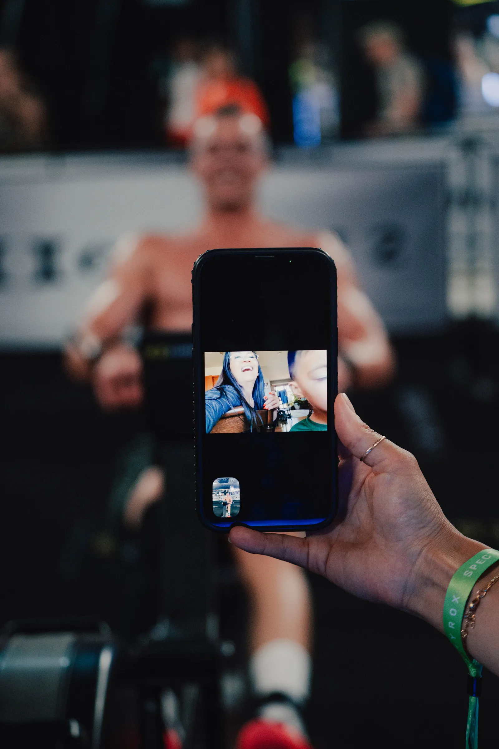 An athlete on the rowing station while family follow the race by video call