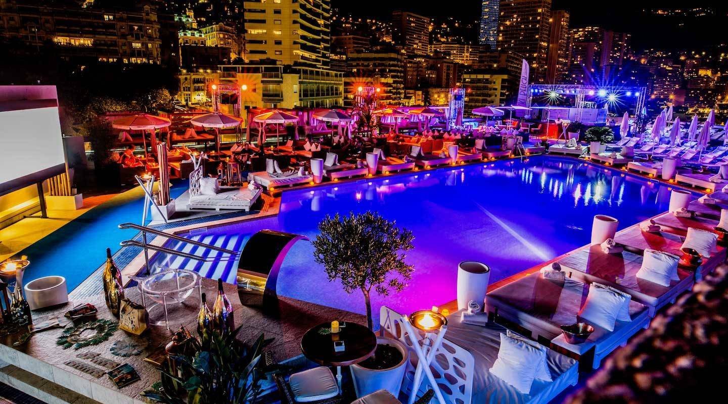 Rooftop terrace with an illuminated pool at night in Monte-Carlo