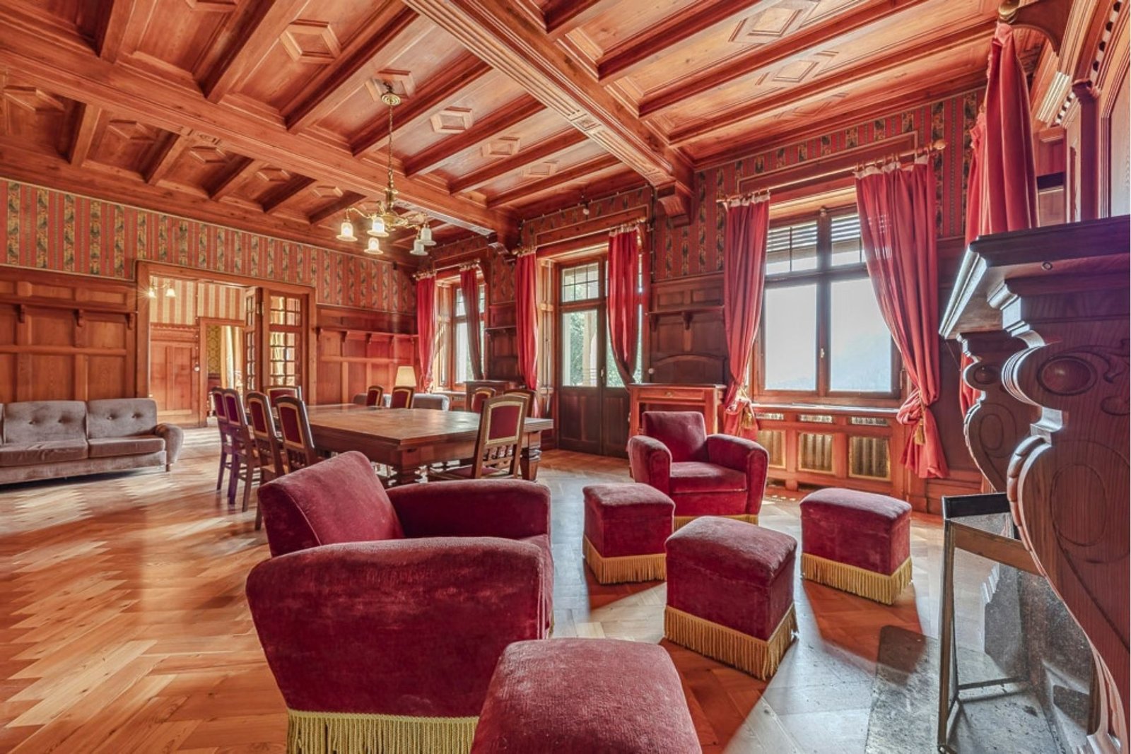 Wood-panelled living room with red armchairs at Villa Laubenò